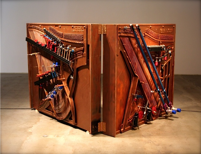 looking like a giant metal book standing open, the player piano is covered in gears and piano string